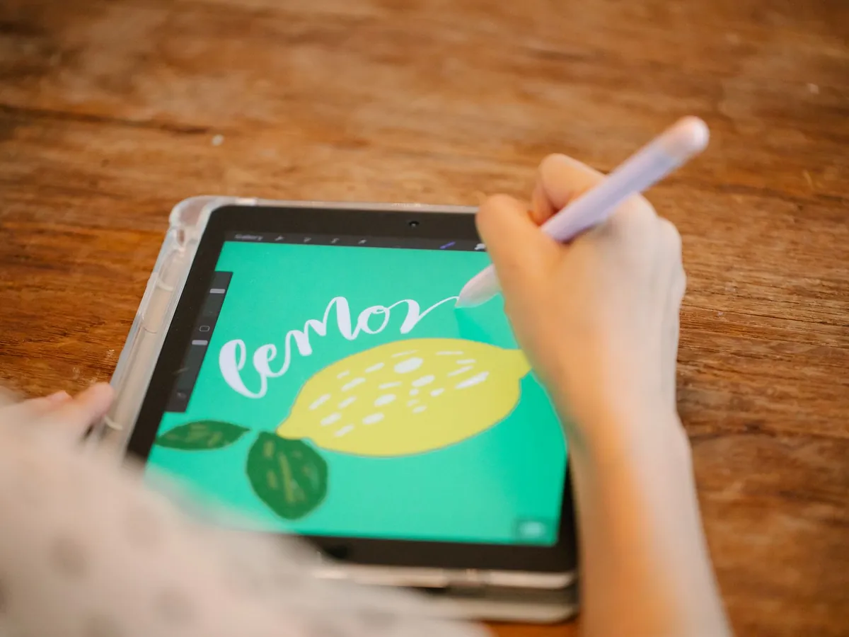 Hand tekent een citroen op een tablet met een stylus op een houten tafel