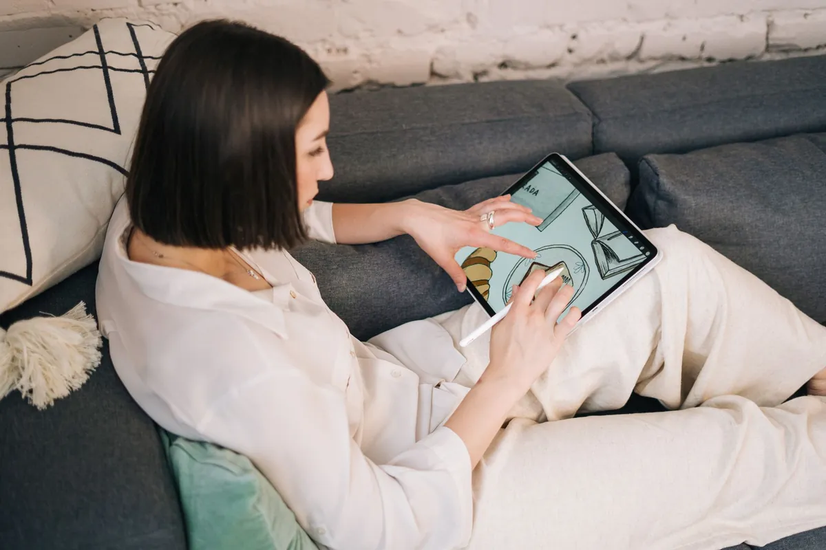 Vrouw op de bank tekent met een pen op een tablet
