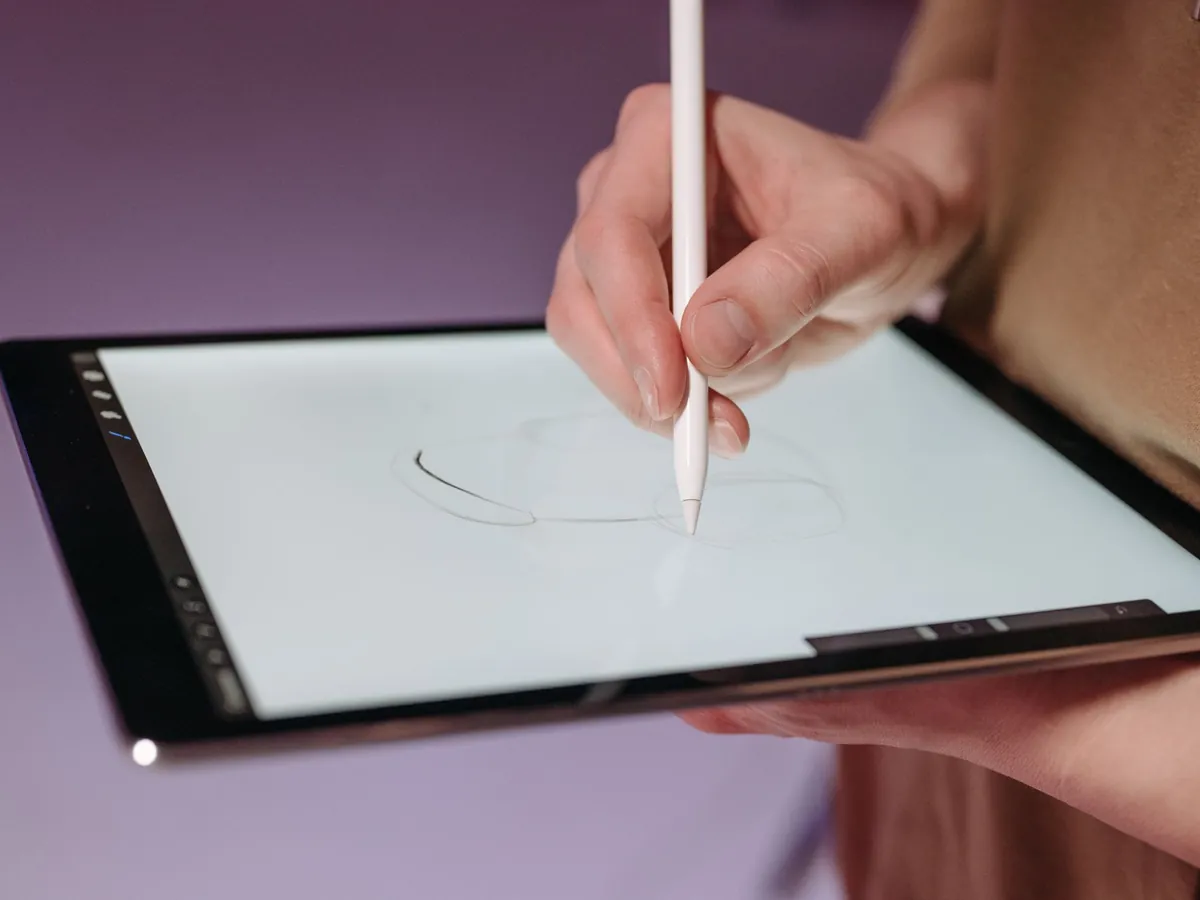 Hand met witte stylus schetst op een tablet tegen een paarse achtergrond