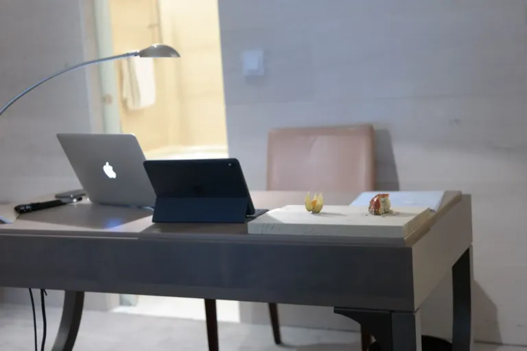 Laptop en tablet naast elkaar op een bureau met een bureaulamp