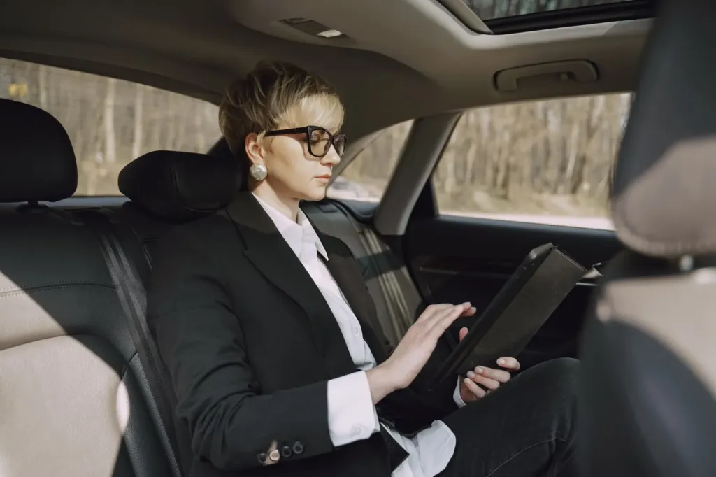 Vrouw op de achterbank van een auto kijkt op een tablet