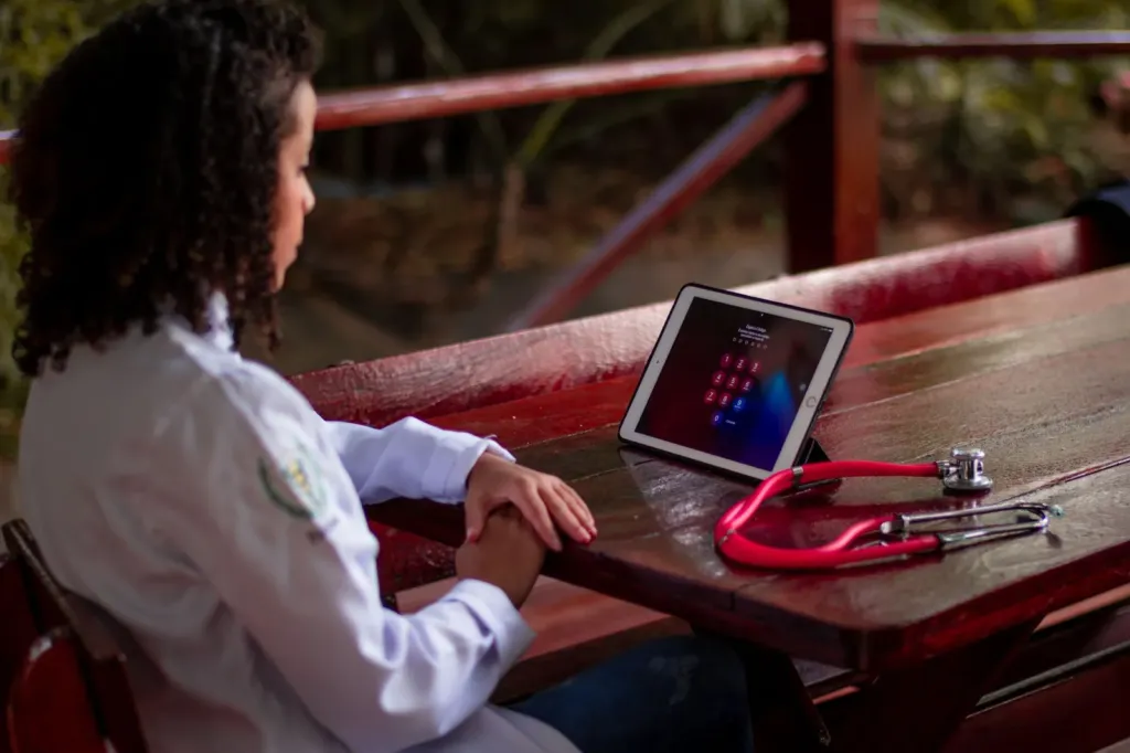 Vrouw aan een houten tafel buiten met een tablet die het vergrendelscherm toont