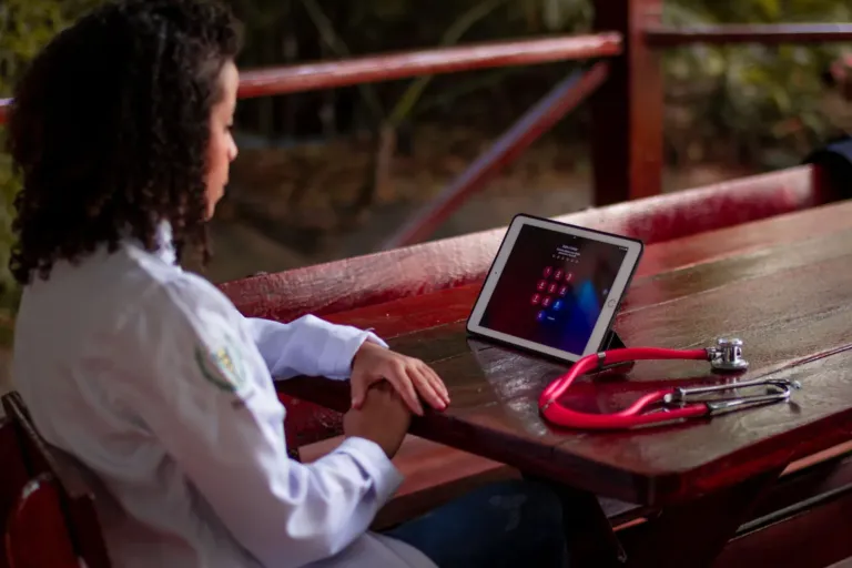 Vrouw aan een houten tafel buiten met een tablet die het vergrendelscherm toont