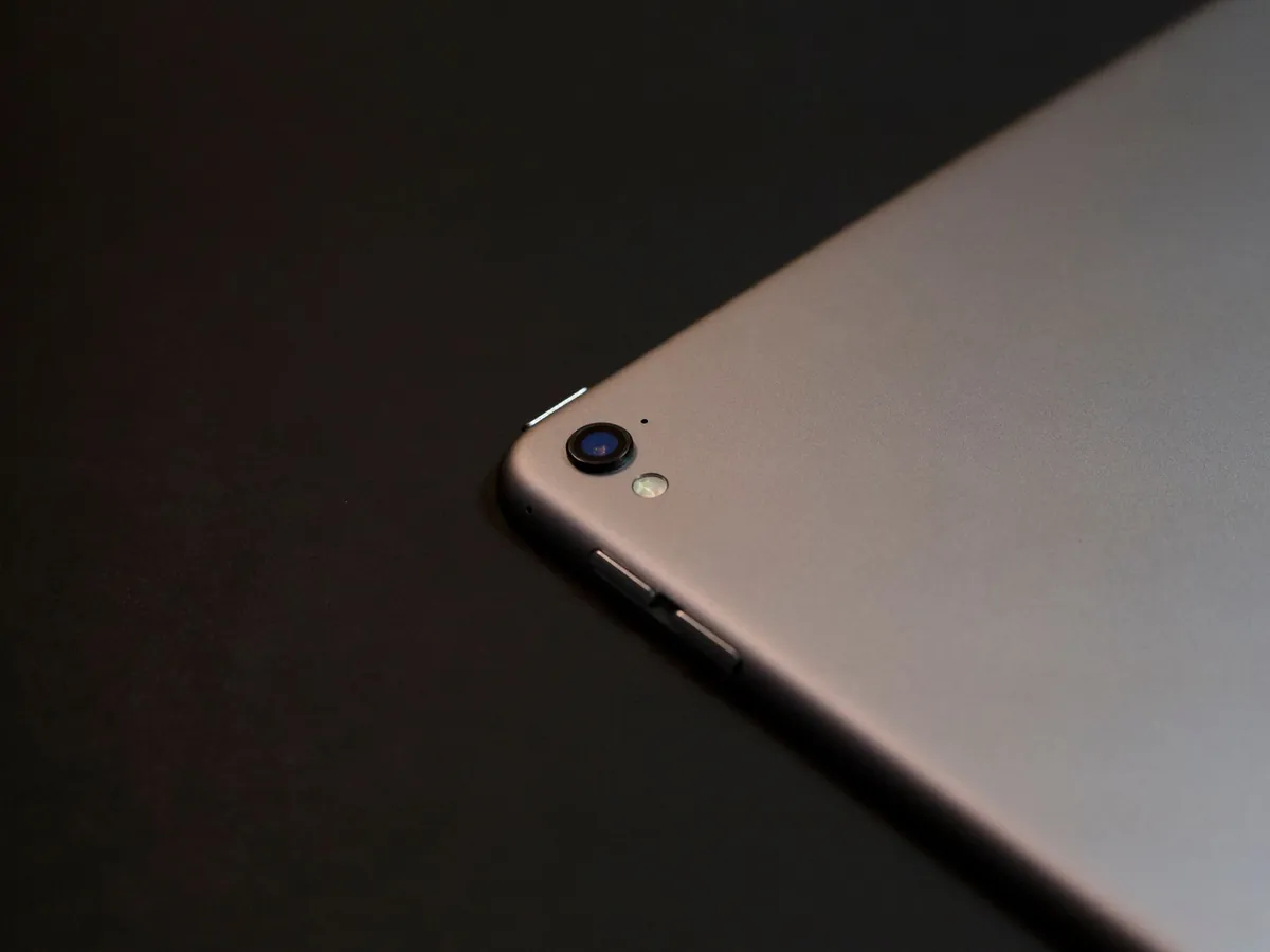 Bovenaanzicht van de hoek van een grijze tablet met camera en knoppen op een zwarte ondergrond